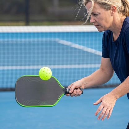 Woman dinking at the net with the green-edge Dinkwell 16 mm honeycomb carbon paddle