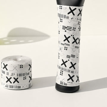 Paddle handle wrapped in a white patterned overgrip beside a spare roll